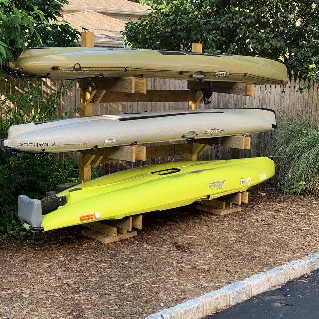 Fishing kayaks stored on a DIY rack made of wood.