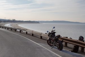 A motorcycle on the side of the road overlooking a cove.