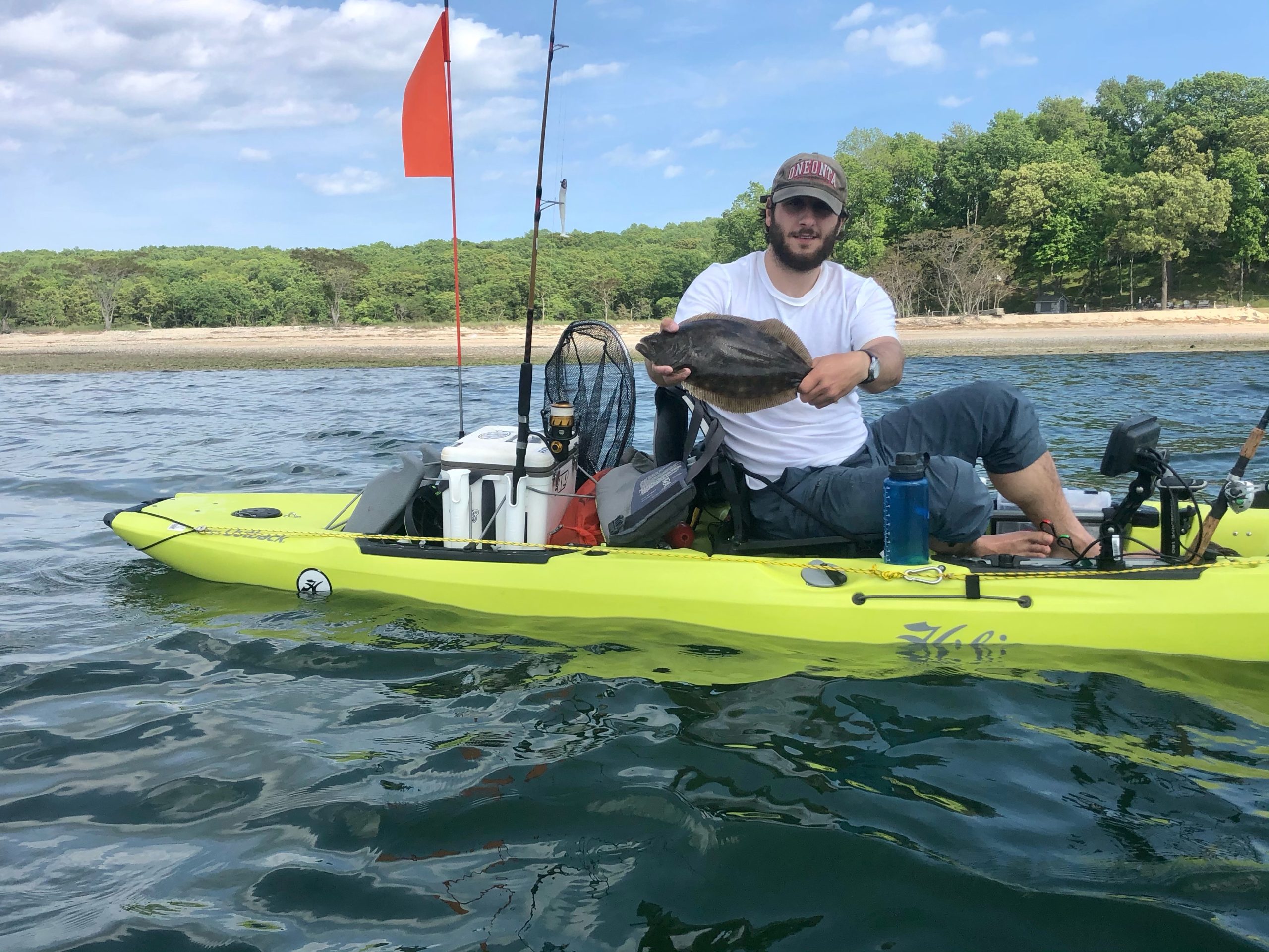 An angler posing with a fish from a hobie mirage outback pedal kayak.